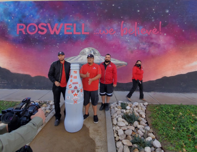 Roswell heroes with the Recognition Roadtrip Bottle at the “We Believe!” mural on Dec. 7, 2021. Located on an external wall of the International UFO Museum & Research Center, this mural created by Larry Bob Phillips in 2019 contrasts the natural beauty of the Roswell skyline with a giant flying saucer.