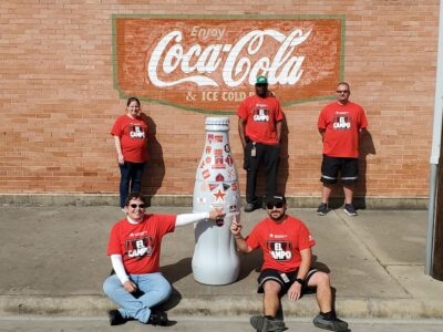 El Campo heroes with the Recognition Roadtrip Bottle on Jan. 6, 2022 in front of the vintage logo mural in the city.