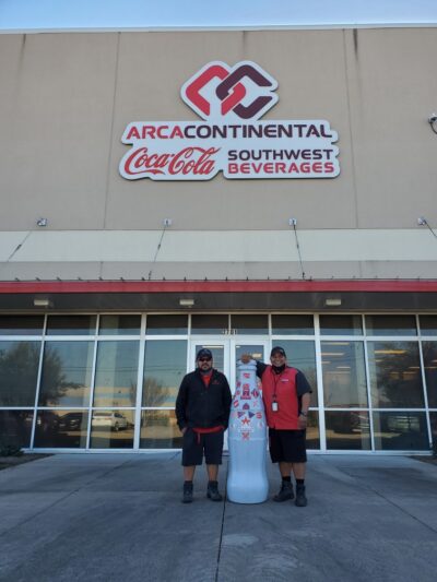 Michael Diaz and Arturo Trejo, Delivery Merchandisers, with the Recognition Roadtrip Bottle outside the Waco CCSWB distribution center.