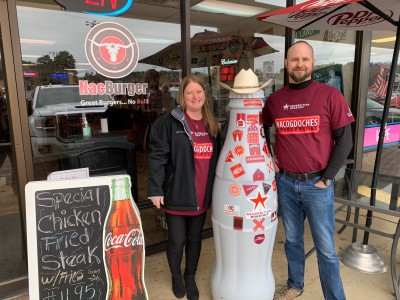 Nacogdoches heroes Kacy Murdock, Market Development Manager (FSOP), and Ryan Dewitt, Route Sales Supervisor, take the Recognition Roadtrip Bottle for a Texas-sized burger at NacBurger on Jan. 20, 2022. NacBurger has been serving burgers to everyone from Stephen F. Austin University students to long-time Nacogdoches residents for more than 40 years.
