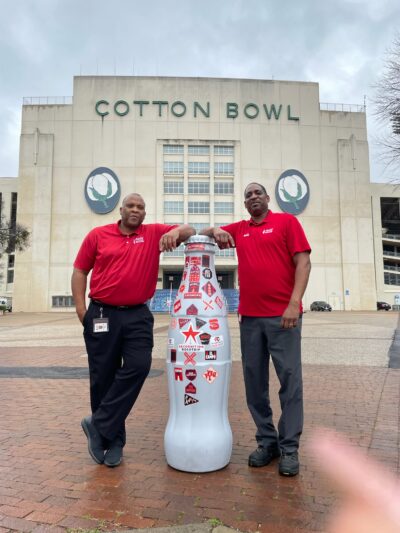 Mesquite heroes Dwayne Packer, Sales Center Manager, and Cardell Armstrong, Warehouse Manager, with the Recognition Roadtrip Bottle at the Cotton Bowl on Feb. 21, 2022.
