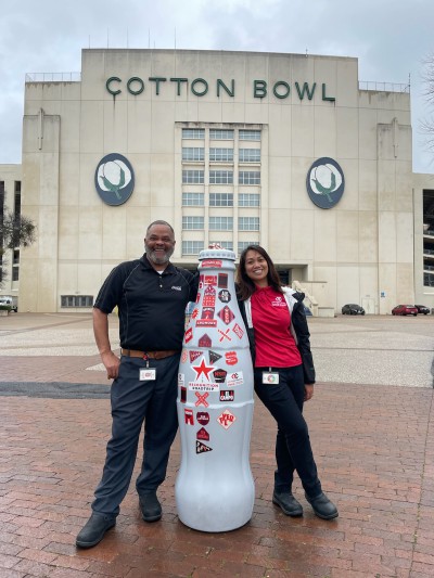 Mesquite heroes Sherman Tyler, Warehouse Manager, and Ria Lee, Warehouse Distribution Supervisor, with the Recognition Roadtrip Bottle at the Cotton Bowl on Feb. 21, 2022.