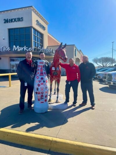 Wichita Falls heroes and the Recognition Roadtrip Bottle share their team “spirit” outside the United Market Street on March 28, 2022. The horse in front of the grocery store, called Spirit, was painted by artist Pam Moller in 2007.