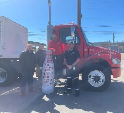 Taking the driver’s seat? The local Wichita Falls drivers pose with the Recognition Roadtrip Bottle and a Coca-Cola truck at their facility on March 28, 2022