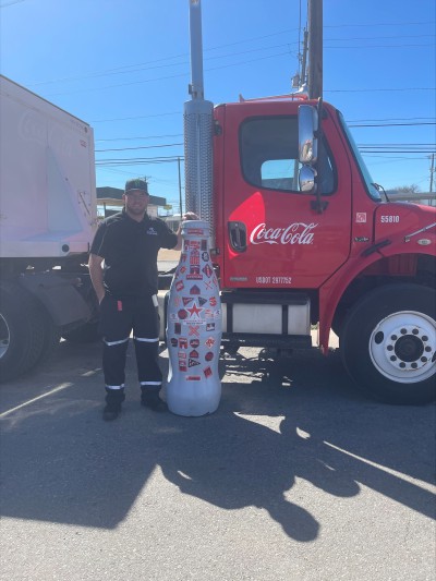 Wichita Falls hero, Cory Hickey, Driver, takes a pic with the Recognition Roadtrip Bottle by a Coca-Cola truck on March 28, 2022 before hitting the road on his route.
