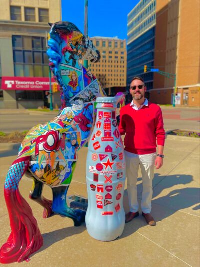 “Whoa there!” Wichita Falls hero Janson Swartz, Order Replenishment Manager, works with the Recognition Roadtrip Bottle to tame the “Choose Your Side” painted horse on March 28, 2022. The horse, which depicts superheroes and villains, was painted by artist Amy Walker in 2017 and is owned today by the Downtown Lion’s Club.