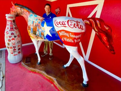 Wichita Falls hero, Lance Bishop, Route Sales Manager, with the Recognition Roadtrip Bottle by the Coca-Cola painted horse outside the CCSWB facility on March 28, 2022. The facility’s horse is affectionately named, “The Real Thing,” and was decorated by artist Chris Ross in 2007.